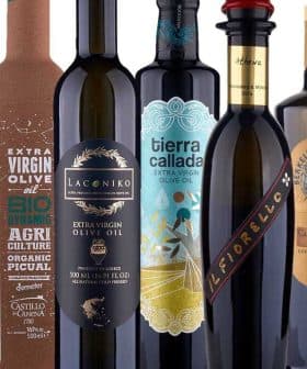 Various bottles of olive oil with distinct labels and designs arranged in a row. - Olive Oil Times