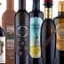 Various bottles of olive oil with distinct labels and designs arranged in a row. - Olive Oil Times