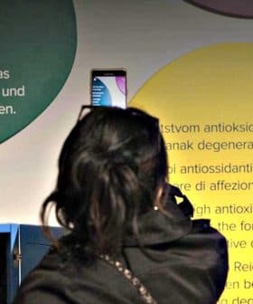 Two women viewing informational displays about health benefits of olive oil at an exhibit. - Olive Oil Times