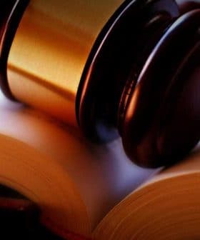 A wooden gavel resting on an open book with blank pages. - Olive Oil Times