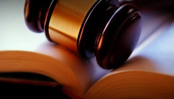 A wooden gavel resting on an open book with blank pages. - Olive Oil Times