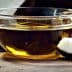 Glass bowl containing coconut oil next to a piece of coconut shell and flesh on a wooden surface. - Olive Oil Times