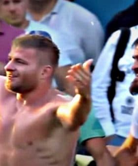 A shirtless wrestler celebrating with a crowd of spectators after a match. - Olive Oil Times
