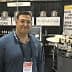 Man standing in front of a booth displaying balsamic vinegar and olive oil products at a trade show. - Olive Oil Times