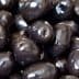 Close-up image of shiny black olives arranged closely together. - Olive Oil Times