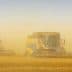 Two combine harvesters working in a field surrounded by dust during harvest season. - Olive Oil Times