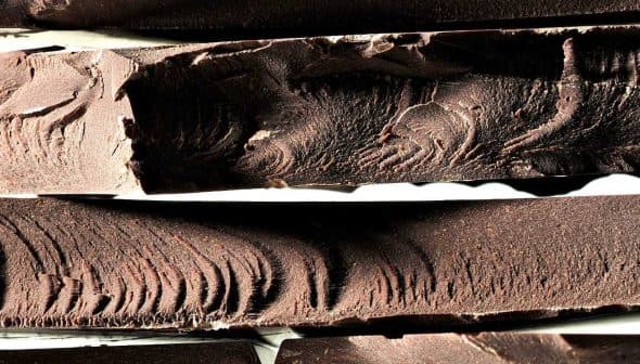Close-up view of several blocks of dark chocolate with textured surfaces. - Olive Oil Times