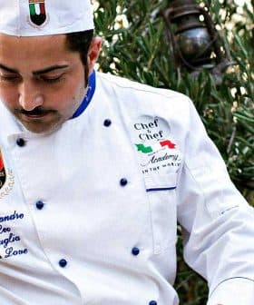 Chef in a white uniform with a hat pouring olive oil from a container. - Olive Oil Times