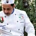 Chef in a white uniform with a hat pouring olive oil from a container. - Olive Oil Times