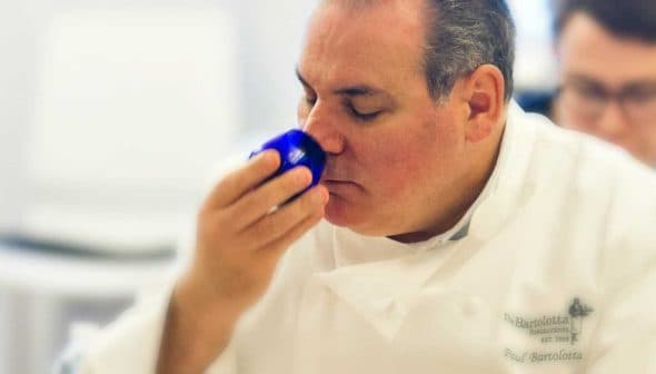 Chef smelling a blue cup during an olive oil tasting session in a professional kitchen. - Olive Oil Times