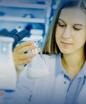 Female scientist examining a beaker containing a liquid in a laboratory setting. - Olive Oil Times