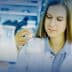 Female scientist examining a beaker containing a liquid in a laboratory setting. - Olive Oil Times