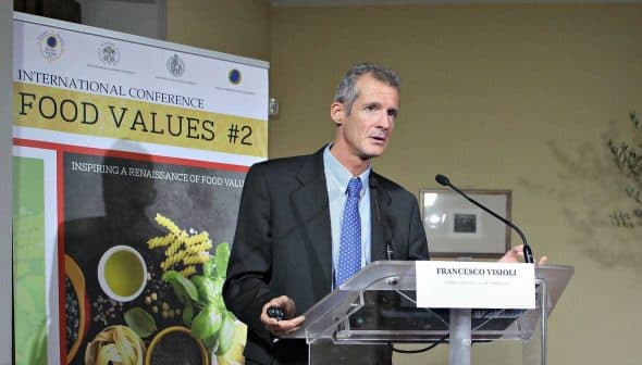 Francesco Visioli speaking at the International Conference on Food Values with a presentation backdrop. - Olive Oil Times
