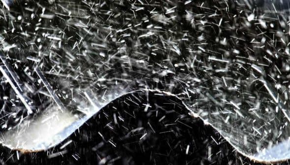 Close-up of water splashing in an abstract wave pattern against a dark background. - Olive Oil Times