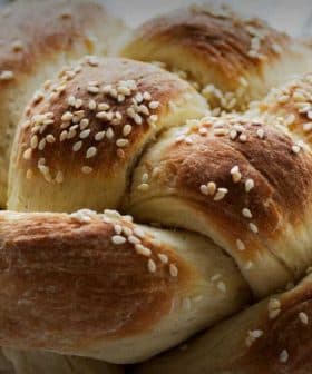 A round loaf of challah bread topped with sesame seeds, showcasing a braided design. - Olive Oil Times