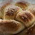 A round loaf of challah bread topped with sesame seeds, showcasing a braided design. - Olive Oil Times