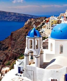 View of Santorini island featuring white buildings with blue domes against the sea. - Olive Oil Times