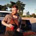 Man with a beard holding a red cup while standing next to a pickup truck in an outdoor setting. - Olive Oil Times