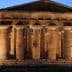 Ancient Greek temple structure with tall columns illuminated at dusk in Paestum, Italy. - Olive Oil Times
