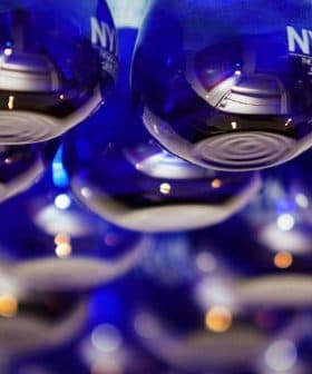 Row of blue glass bottles labeled 'NYIOOC' arranged in a display. - Olive Oil Times