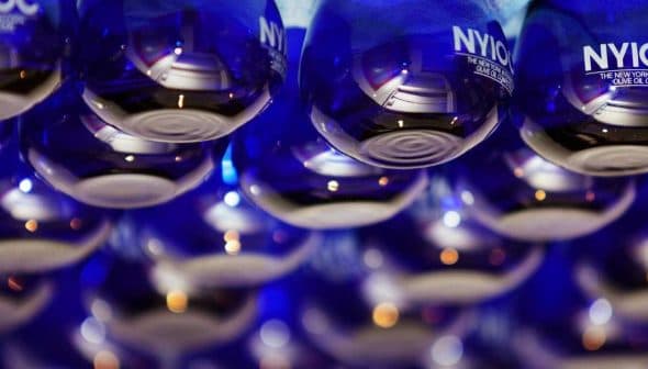 Row of blue glass bottles labeled 'NYIOOC' arranged in a display. - Olive Oil Times