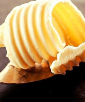 A portion of butter shaped in ridges resting on a metal butter knife. - Olive Oil Times