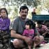 A family sitting together during a break from harvesting, with children and adults in casual clothing. - Olive Oil Times