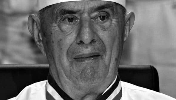 Black and white portrait of an elderly chef wearing a white uniform and hat. - Olive Oil Times