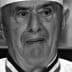 Black and white portrait of an elderly chef wearing a white uniform and hat. - Olive Oil Times