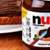 Jar of Nutella hazelnut spread next to a slice of bread topped with the spread. - Olive Oil Times