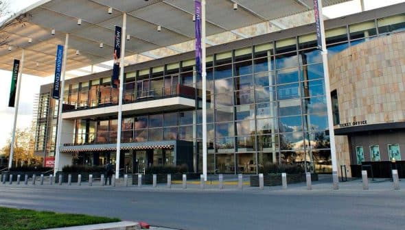 A modern commercial building featuring a glass facade and multiple banners. - Olive Oil Times