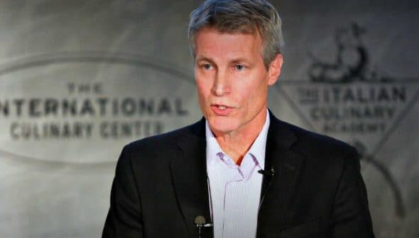 A man delivering a presentation at the International Culinary Center with a microphone attached. - Olive Oil Times