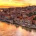 A panoramic view of Porto's riverfront at sunset with colorful buildings along the water's edge. - Olive Oil Times
