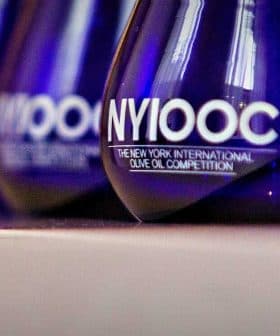 Blue glass awards with 'NYIOOC The New York International Olive Oil Competition' text displayed in a row. - Olive Oil Times