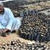 Two men preparing seedling pots filled with soil in a garden setting. - Olive Oil Times