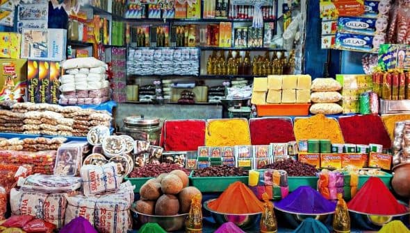A variety of colorful spices, snacks, and packaged goods arranged in a market setting. - Olive Oil Times