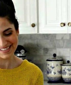 Woman with long dark hair wearing a yellow sweater while preparing food in a kitchen. - Olive Oil Times