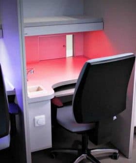 Four office workstations with ergonomic chairs and adjustable lighting in various colors. - Olive Oil Times