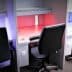 Four office workstations with ergonomic chairs and adjustable lighting in various colors. - Olive Oil Times