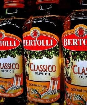 Row of Bertolli olive oil bottles in various types including Classico and Extra Light. - Olive Oil Times