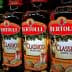 Row of Bertolli olive oil bottles in various types including Classico and Extra Light. - Olive Oil Times