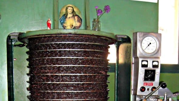 Olive oil pressing machine with a religious icon and flowers on top of it. - Olive Oil Times
