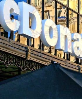 Signage of a McDonald's restaurant with reflective glass facade in the background. - Olive Oil Times