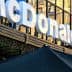 Signage of a McDonald's restaurant with reflective glass facade in the background. - Olive Oil Times
