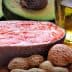 Raw salmon fillet placed on a wooden board alongside avocado, nuts, and olive oil. - Olive Oil Times