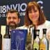 Two individuals giving thumbs up while posing with various olive oil bottles and awards. - Olive Oil Times