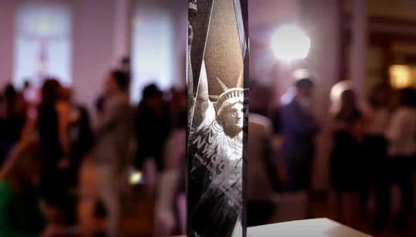 Statue of Liberty model displayed prominently at an indoor event with blurred background attendees. - Olive Oil Times