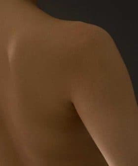 Close-up view of a bare back showing smooth skin and shoulder contours against a dark background. - Olive Oil Times