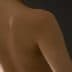 Close-up view of a bare back showing smooth skin and shoulder contours against a dark background. - Olive Oil Times