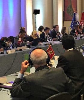 A conference room with delegates seated around a large table during a meeting. - Olive Oil Times
